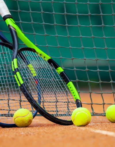 Two tennis rackets and balls leaned against the net.