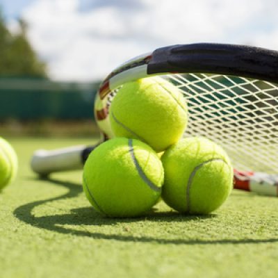 49750172 - tennis balls and racket on the grass court